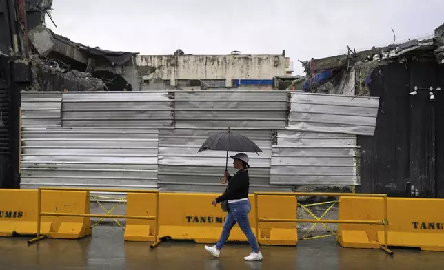A woman walks past the rubble of Jet Set nightclub days after its roof collapsed, killing more than 200 people, in Santo Domingo, Dominican Republic, Friday, April 11, 2025. (AP Photo/Matias Delacroix)