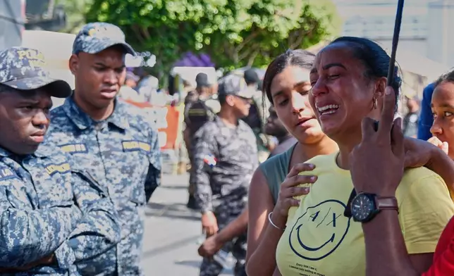 A relative of a missing person is comforted by a friend outside Jet Set nightclub after its roof collapsed during a merengue concert in Santo Domingo, Dominican Republic, Tuesday, April 8, 2025. (AP Photo/Ricardo Hernandez)