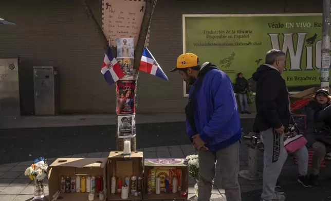 A person looks at a makeshift vigil for the victims of the Jet Set club roof collapse, Wednesday, April 9, 2025, in New York. (AP Photo/Adam Gray)