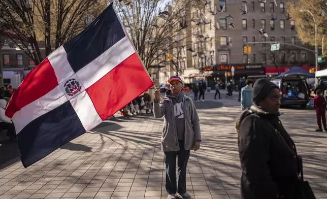 Johnny Martinez, 65, from the Dominican Republic, holds the Dominican Republic flag near a makeshift vigil for the victims of the Jet Set club roof collapse, Wednesday, April 9, 2025, in New York. (AP Photo/Adam Gray)