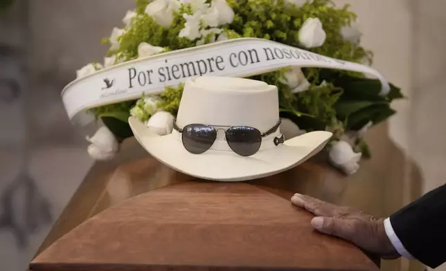 The hat and sunglasses of Dominican singer Rubby Perez, who died in the roof collapse at the Jet Set nightclub during his merengue concert, sit on his casket during his wake at the Eduardo Brito National Theater in Santo Domingo, Dominican Republic, Thursday, April 10, 2025. (AP Photo/Matias Delacroix)
