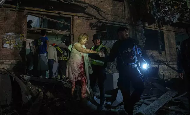 Police officers guide an injured woman out of her house, which was damaged by a Russian airstrike, in a residential neighbourhood in Kyiv, Ukraine, on Thursday, April 24, 2025. (AP Photo/Evgeniy Maloletka)