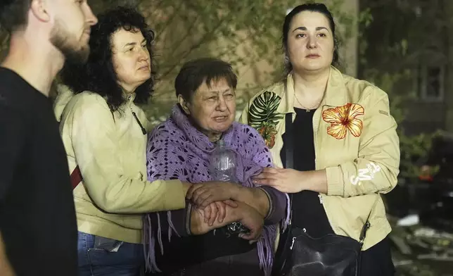 Local residents react at the site of an apartment building hit by a Russian ballistic missile attack in Kyiv, Ukraine, early Thursday, April 24, 2025. (AP Photo/Efrem Lukatsky)