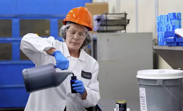 Technician Heather Browning pours a liquid color sample into a smaller container to be shipped to a customer at Sensient Technologies Corp., a color additive manufacturing company, in St. Louis., on Wednesday, April 2, 2025. (AP Photo/Jeff Roberson)