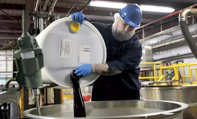 Caleb Whorl pours a container of caramel coloring into a vat to be mixed before packaging at Sensient Technologies Corp., a color additive manufacturing company, in St. Louis, on Wednesday, April 2, 2025. (AP Photo/Jeff Roberson)