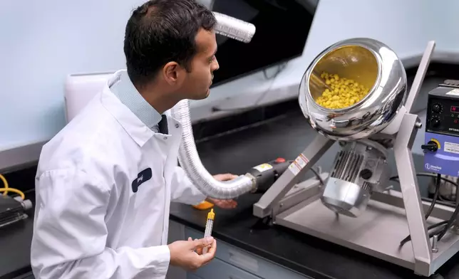 Applications Scientist Anuj Bag watches candy spin inside a drum while being coated with yellow coloring as he demonstrates the process of developing new food colors at Sensient Technologies Corp., a color additive manufacturing company, in St. Louis, on Wednesday, April 2, 2025. (AP Photo/Jeff Roberson)