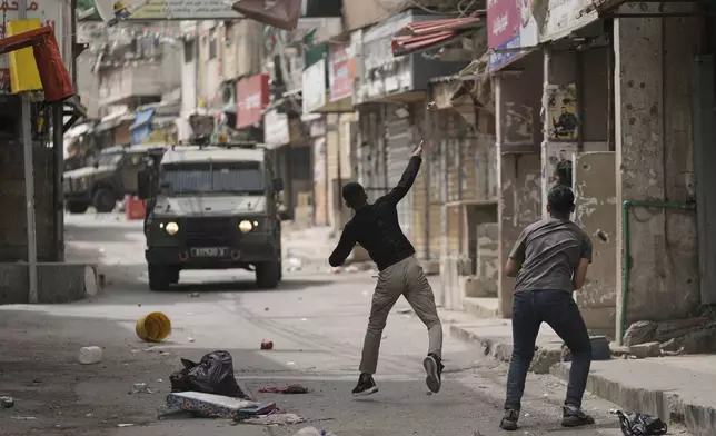 Palestinians hurls a stone at Israeli forces following a military raid in the West Bank refugee camp of Balata, on Wednesday, April 9, 2025. (AP Photo/Majdi Mohammed)
