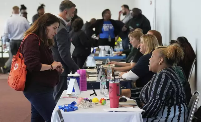 Shea Giagnorio, left, talks to a recruiter at a job fair on the day she was laid off from her job at the Administration for Children and Families, Tuesday, April 1, 2025, in Kansas City, Mo. (AP Photo/Charlie Riedel)