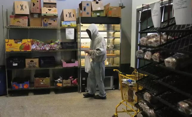 A man collects food staples at the Bishop Sullivan Center food pantry, Tuesday, April 15, 2025, in Kansas City, Mo. (AP Photo/Charlie Riedel)