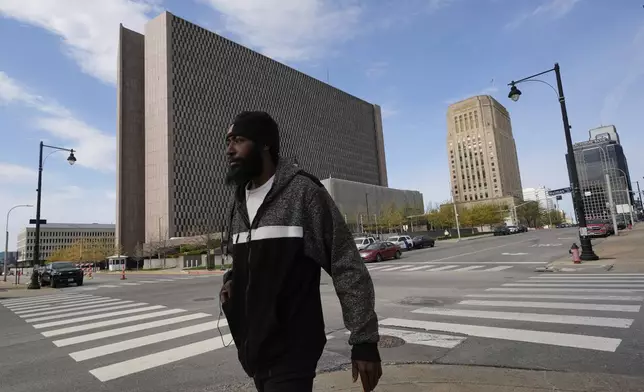 A pedestrian walks past the The Richard Bolling federal building, left, Monday, April 14, 2025, in Kansas City, Mo. (AP Photo/Charlie Riedel)