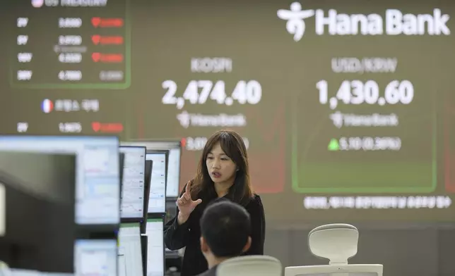 ADDS THE NAME OF THE BANK - Employees of Hana Bank talk near the screens showing the Korea Composite Stock Price Index (KOSPI), center, and the foreign exchange rate between U.S. dollar and South Korean won at a foreign exchange dealing room in Seoul, South Korea, Wednesday, April 16, 2025. (AP Photo/Lee Jin-man)