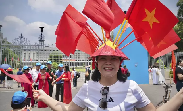 //A woman wears a conical hat decorated with Vietnamese flags to celebrate the 50th anniversary of the end of the Vietnam War in front of the Independence Palace in Ho Chi Minh City, Vietnam Tuesday, April 29, 2025. (AP Photo/Hau Dinh)