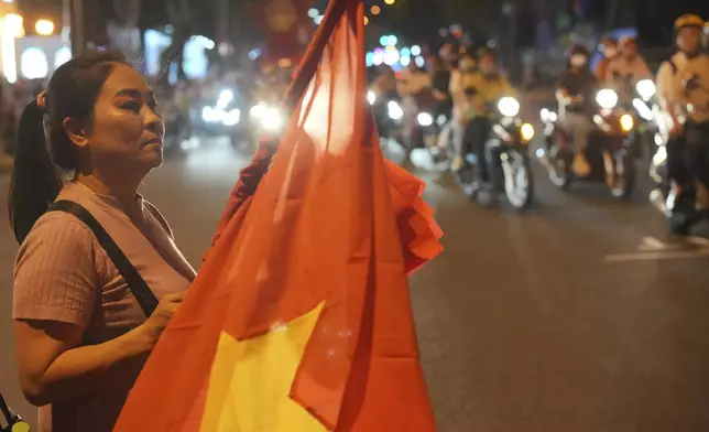 A women hold Vietnam national flag ahead of the 50th anniversary of the end of the Vietnamese War at a street in Ho Chi Minh City, Vietnam, Tuesday, April 29, 2025. (AP Photo/Achmad Ibrahim)