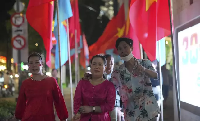 People walk in a street decorated for the 50th anniversary of the end of the Vietnamese War in Ho Chi Minh City, Vietnam, Tuesday, April 29, 2025.(AP Photo/Achmad Ibrahim)