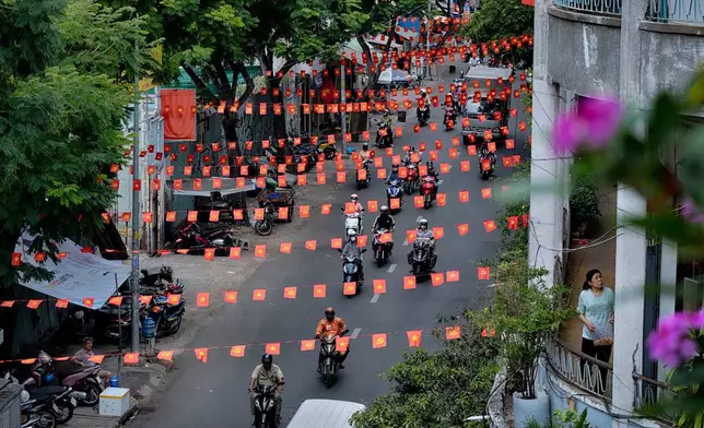 Motorbikes drive along a street under Vietnamese flags in the Cholon district of Ho Chi Minh City, Vietnam, on Tuesday, April 29, 2025 ahead of the 50th anniversary of the end of the Vietnamese War. (AP Photo/Richard Vogel)