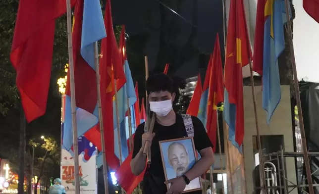 A man walks with a portrait of Vietnamese national hero Ho Chi Minh ahead of the 50th anniversary of the end of the Vietnamese War in Ho Chi Minh City, Vietnam, Tuesday, April 29, 2025.(AP Photo/Achmad Ibrahim)