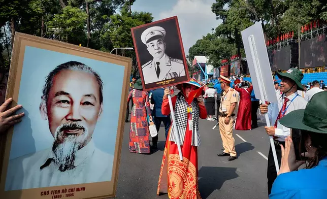 A woman is photographed with a photo of the late wartime Vietnamese Gen. Vo Nguyen Giap as another person holds a photo of the late Vietnamese revolutionary leader Ho Chi Minh, left, after a parade celebrating the 50th anniversary of the end of the Vietnam War on Wednesday, April 30, 2025, in Ho Chi Minh City, Vietnam. (AP Photo/Richard Vogel)