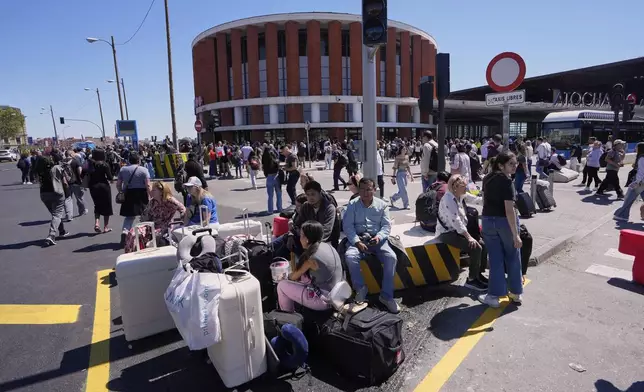 Passengers roam outside Atocha train station during a nationwide power outage in Madrid, Monday, April 28, 2025. (AP Photo/Manu Fernandez)