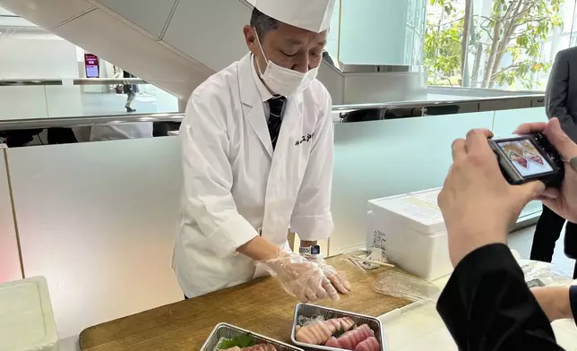 Sushi chef Junichi Kurita demonstrates how the fatty tuna looks different from the leaner kind, and serves it with soy sauce and wasabi relish to reporters April 9, 2025 at a Fujitsu facility in Kawasaki, outside Tokyo. (AP Photo/Yuri Kageyama)