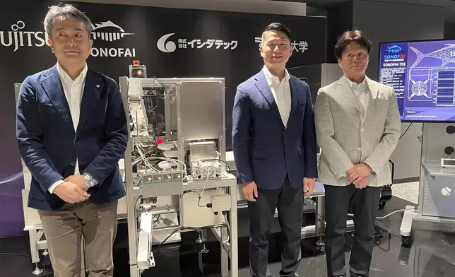 From left, Hideto Okada, a Fujitsu official in charge of AI, Hisashi Ishida, the head of startup Sonofai and Ishida Tec, and Keiichi Goto, professor at Tokai University pose in front of a machine called Sonofai, at a Fujitsu facility in Kawasaki, Japan Wednesday, April 9, 2025. (AP Photo/Yuri Kageyama)