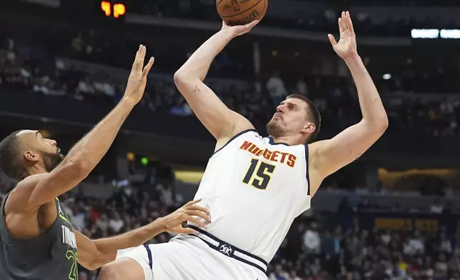 Denver Nuggets center Nikola Jokic, right, shoots for a basket over Minnesota Timberwolves center Rudy Gobert in the first half of an NBA basketball game Tuesday, April 1, 2025, in Denver. (AP Photo/David Zalubowski)