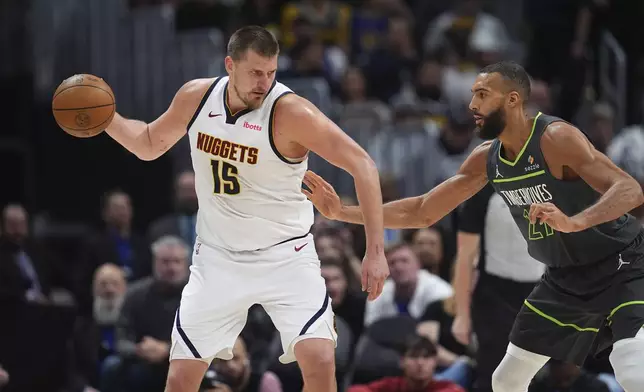 Denver Nuggets center Nikola Jokic, left, looks to pass the ball as Minnesota Timberwolves center Rudy Gobert defends in the second half of an NBA basketball game Tuesday, April 1, 2025, in Denver. (AP Photo/David Zalubowski)