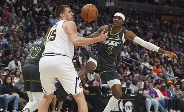 Denver Nuggets center Nikola Jokic, left, pursues a loose ball with Minnesota Timberwolves forward Jaden McDaniels in the second half of an NBA basketball game Tuesday, April 1, 2025, in Denver. (AP Photo/David Zalubowski)