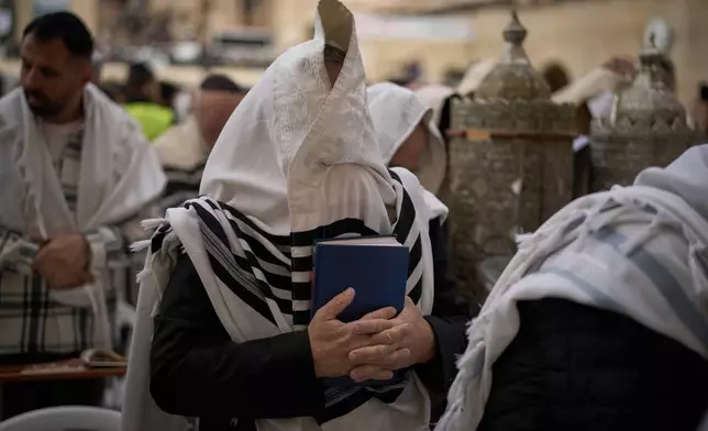 Covered in prayer shawls, a Jewish man of the Cohanim Priestly caste participates in a blessing during the holiday of Passover, at the Western Wall, the holiest site where Jews can pray, in the Old City of Jerusalem, Tuesday, April 15, 2025. (AP Photo/Leo Correa)