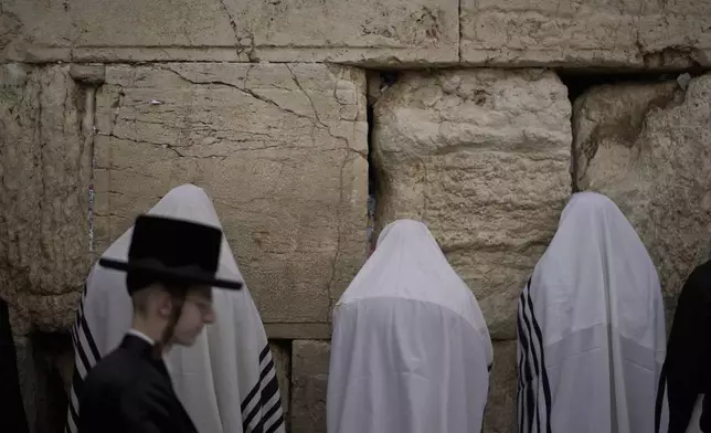 Covered in prayer shawls, Jewish men of the Cohanim Priestly caste participate in a blessing during the holiday of Passover, at the Western Wall, the holiest site where Jews can pray, in the Old City of Jerusalem, Tuesday, April 15, 2025. (AP Photo/Leo Correa)