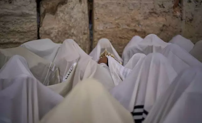 Covered in prayer shawls, Jewish men of the Cohanim Priestly caste participate in a blessing during the holiday of Passover, at the Western Wall, the holiest site where Jews can pray, in the Old City of Jerusalem, Tuesday, April 15, 2025. (AP Photo/Leo Correa)
