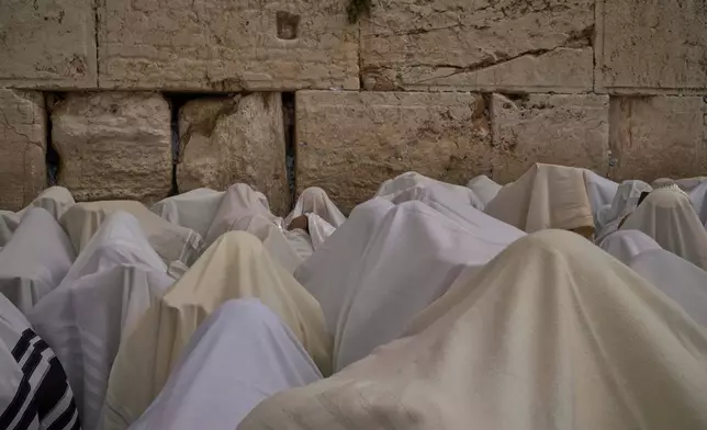 Covered in prayer shawls, Jewish men of the Cohanim Priestly caste participate in a blessing during the holiday of Passover, at the Western Wall, the holiest site where Jews can pray, in the Old City of Jerusalem, Tuesday, April 15, 2025. (AP Photo/Leo Correa)