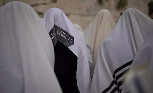 Covered in prayer shawls, Jewish men of the Cohanim Priestly caste participate in a blessing during the holiday of Passover, at the Western Wall, the holiest site where Jews can pray, in the Old City of Jerusalem, Tuesday, April 15, 2025. (AP Photo/Leo Correa)