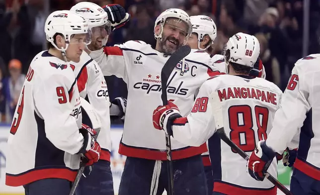 Washington Capitals left wing Alex Ovechkin, center, celebrates with teammates after scoring his 895th career goal during the second period of an NHL hockey game against the New York Islanders, in Elmont, N.Y., April 6, 2025. (AP Photo/Adam Hunger)