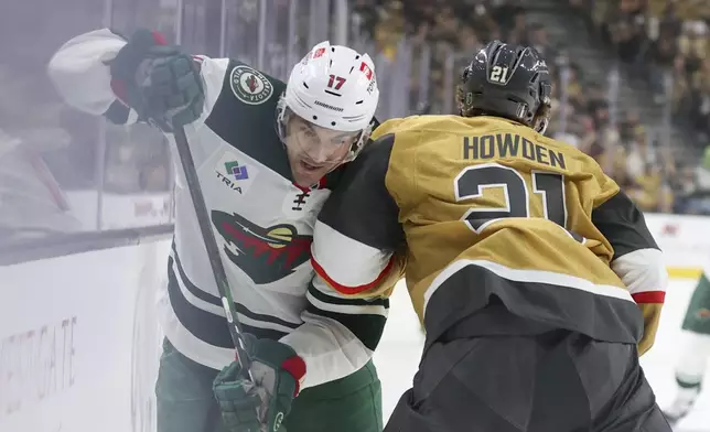 Vegas Golden Knights center Brett Howden (21) checks Minnesota Wild left wing Marcus Foligno (17) during the first period in Game 1 of an NHL hockey Stanley Cup first-round playoff series Sunday, April 20, 2025, in Las Vegas. (AP Photo/Ian Maule)