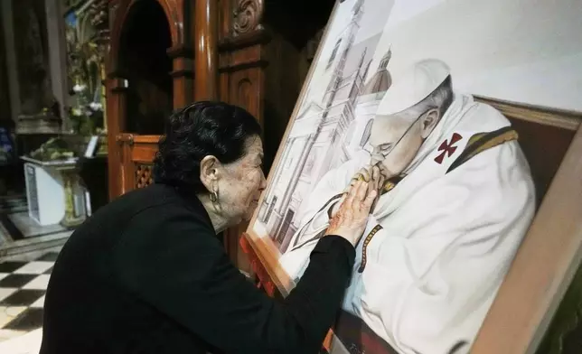 Genali Nogales touches a painting of the late Pope Francis at the Basílica de San José de Flores, where he worshipped as a youth, following the Vatican's announcement of his death in Buenos Aires, Argentina, Monday, April 21, 2025. (AP Photo/Gustavo Garello)
