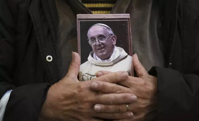 A faithful holds a portrait of late Pope Francis at the Basílica de San José de Flores, where he worshipped as a youth, following the Vatican's announcement of his death in Buenos Aires, Argentina, Monday, April 21, 2025. (AP Photo/Gustavo Garello)