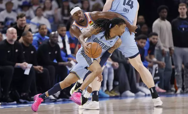 Memphis Grizzlies guard Ja Morant, front, drives past Oklahoma City Thunder guard Luguentz Dort, upper left, as Grizzlies center Zach Edey (14) screens during the first half in Game 1 of an NBA first-round playoff series, Sunday, April 20, 2025, in Oklahoma City. (AP Photo/Nate Billings)