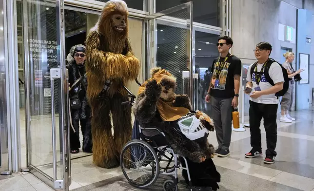 Star Wars fans wearing costumes of Chewbacca, left, and Widdle Warrick, pose for a photo during a fan convention called the Star Wars Celebration in Chiba, near Tokyo, Friday, April 18, 2025. (AP Photo/Hiro Komae)