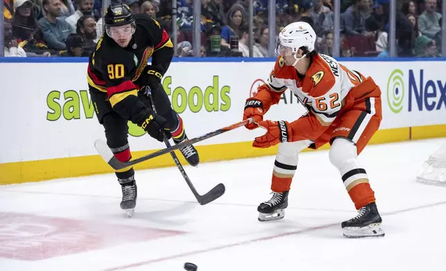 Vancouver Canucks' Victor Mancini (90) clears the puck as Anaheim Ducks' Nikita Nesterenko (62) attacks during the second period of an NHL game in Vancouver, on Saturday, April 5, 2025. (Ethan Cairns/The Canadian Press via AP)