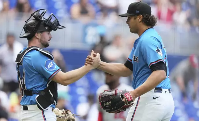Miami Marlins catcher Liam Hicks, left, and relief pitcher Tyler Phillips, right, shake hands after the Marlins defeated the Washington Nationals in a baseball game, Sunday, April 13, 2025, in Miami. (AP Photo/Lynne Sladky)