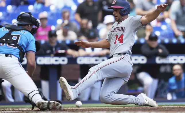 Washington Nationals shortstop Paul DeJong (14) scores on a single hit by Alex Call during the fourth inning of a baseball game against the Miami Marlins, Sunday, April 13, 2025, in Miami. (AP Photo/Lynne Sladky)