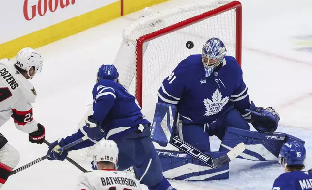 Ottawa Senators' Dylan Cozens (24) takes a shot on Toronto Maple Leafs goaltender Anthony Stolarz (41) while being defended by Toronto Maple Leafs' Simon Benoit (2) during second period NHL playoff action in Toronto on Tuesday, April 22, 2025. (Cole Burston/The Canadian Press via AP)
