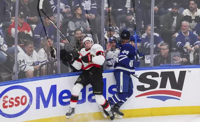 Ottawa Senators' Drake Batherson (19) and Toronto Maple Leafs' Morgan Rielly (44) collide along the boards during second period NHL playoff action in Toronto on Tuesday, April 22, 2025. (Nick Iwanyshyn/The Canadian Press via AP)