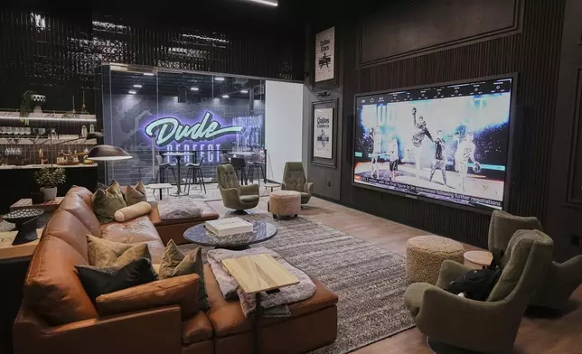 A large projection screen, couches and other amenities fill one of the work spaces at Dude Perfect's new headquarters in Frisco, Texas, Wednesday, Feb. 19, 2025. (AP Photo/Tony Gutierrez)