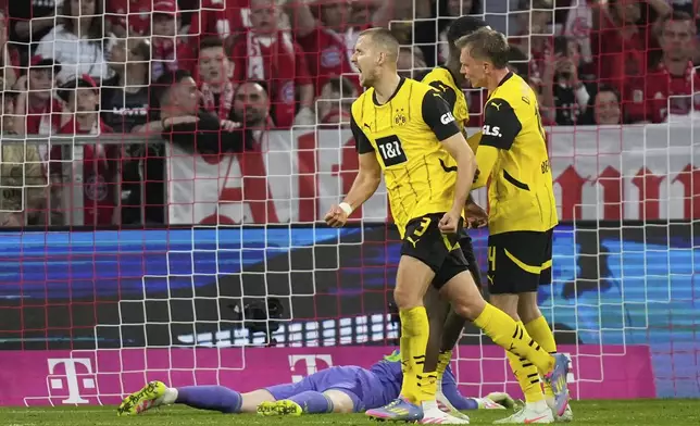 Dortmund's Waldemar Anton, centre, celebrates after scoring his side's second goal during the German Bundesliga soccer match between Bayern Munich and Borussia Dortmund at the Allianz Arena in Munich, Germany, Saturday, April 12, 2025. (AP Photo/Matthias Schrader)