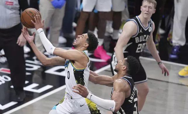 Indiana Pacers guard Tyrese Haliburton (0) shoots the ball past Milwaukee Bucks forward Giannis Antetokounmpo, right, during the second half in Game 5 of an NBA basketball first-round playoff series in Indianapolis, Tuesday, April 29, 2025. (AP Photo/Michael Conroy)