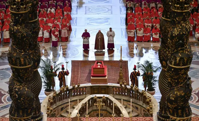 Gianlorenzo Bernini's monumental canopy serves as a dramatic frame as Cardinal Camerlengo Kevin Joseph Farrell, with Masters of ceremonies, Archbishop Diego Giovanni Ravelli, left, and Monsignor Krzysztof Marcjanowicz, right, prays in front of Pope Francis's body into St. Peter's Basilica at the Vatican on Wednesday, April 23, 2025, where the deceased pontiff will lie in state for three days. (Vatican Media via AP)
