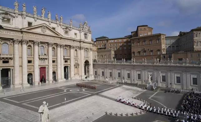 People watch in St. Peter's Square the procession of the arrival of the body of Pope Francis, who will lie in state at St. Peter's Basilica for three days, at the Vatican, Wednesday, April 23, 2025. (AP Photo/Gregorio Borgia)