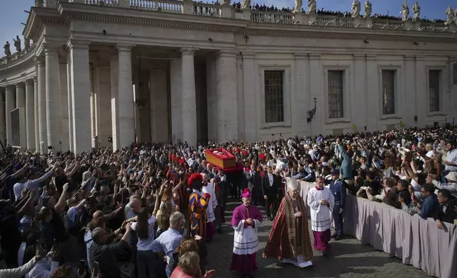The body of Pope Francis is carried into St. Peter's Basilica at the Vatican, Wednesday, April 23, 2025, where he will lie in state for three days. (AP Photo/Emilio Morenatti)