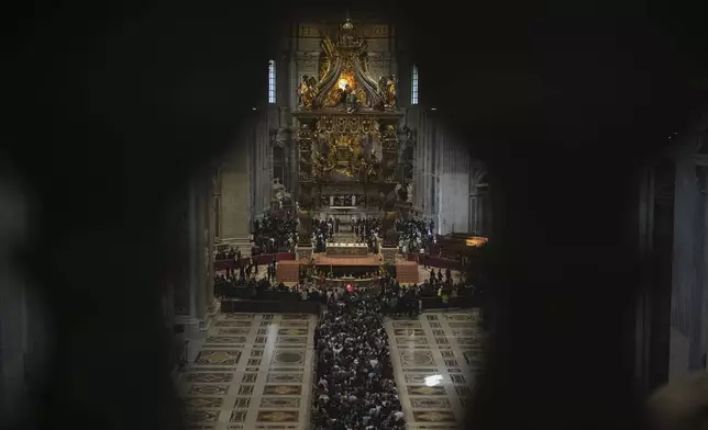 Balcony columns frame the queue of people lining up to pay their respects to Pope Francis lying in state, inside St. Peter's Basilica, at the Vatican, Friday, April 25, 2025. (AP Photo/Andrew Medichini)